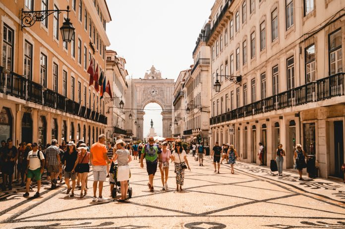 European city tourism pressure — Voyazure Travelers walking through a busy historic European city centre