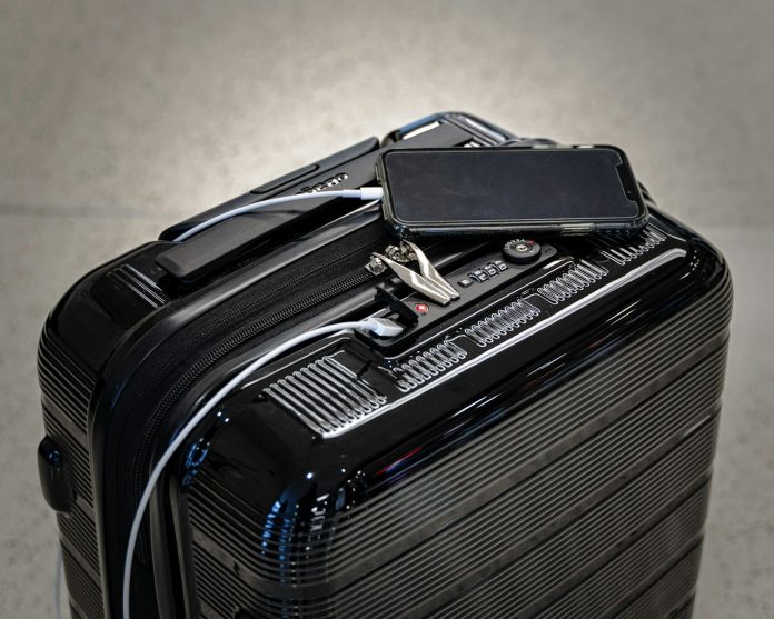 Power bank and carry-on luggage A traveler charging a smartphone from a power bank beside carry-on luggage